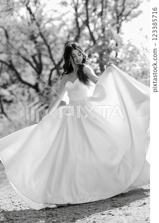 a young girl bride in a white dress is spinning on a path 123385716
