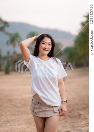 Beautiful smiling Thai girl wearing a white T-shirt and a cute short skirt in a public park. Beautiful smiling Thai girl wearing a white T-shirt and a cute short skirt in a public park. 123385736