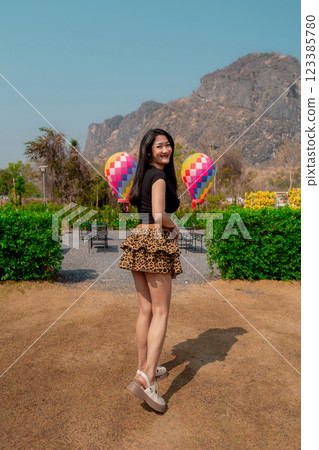 A cute smiling woman wearing a black dress and a tiger-print skirt in an outdoor cafe. A cute smiling woman wearing a black dress and a tiger-print skirt in an outdoor cafe. 123385780