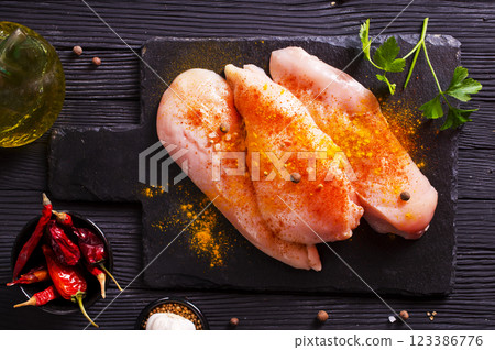 Raw fresh chicken fillet on black stone board Raw fresh chicken fillet on black stone board 123386776