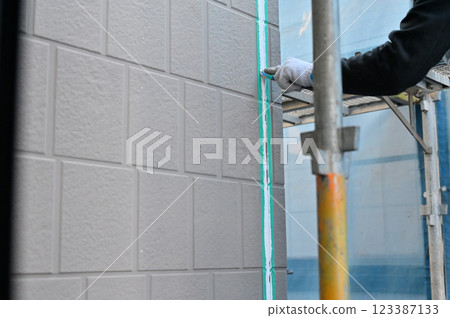 A craftsman smoothing out the caulking with a spatula - Exterior wall painting work - Replacing the caulking 123387133