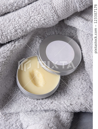 Opened body butter jar with blank label on light grey bath towel close up, cosmetic mockup 123387176