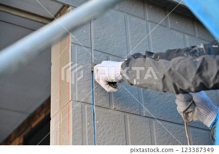 A craftsman removing old caulking, replacing caulking, exterior wall painting work A craftsman removing old caulking, replacing caulking, exterior wall painting work 123387349