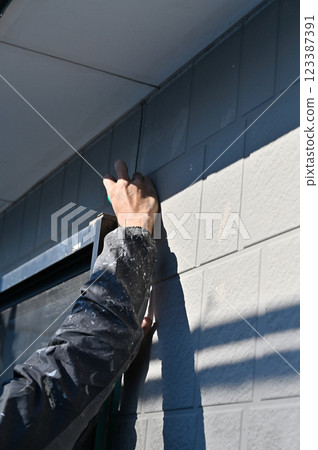 一名工匠遮蓋牆壁、更換填縫劑、進行外牆粉刷工作 一名工匠遮蓋牆壁、更換填縫劑、進行外牆粉刷工作 123387391