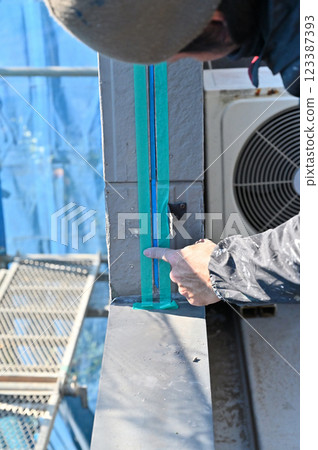 A craftsman masking a wall, replacing caulking, exterior wall painting work 123387393