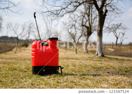 Red sprayer in spring garden Red sprayer in spring garden 123387524
