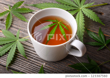 White cup of cannabis tea with fresh green marijuana leaves 123387560