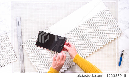 Flat lay. In the process of mounting peel and stick mosaic tiles onto a foam board, perfect for enhancing a food photography studio's aesthetic. Flat lay. In the process of mounting peel and stick mosaic tiles onto a foam board, perfect for enhancing a food photography studio's aesthetic. 123387946