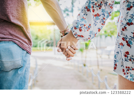 Close up of couple holding hands outdoors, Close up of young couple walking holding hands. Close-up of teenagers holding hands in a park. View of young couple holding hands outdoors Close up of couple holding hands outdoors, Close up of young couple walking holding hands. Close-up of teenagers holding hands in a park. View of young couple holding hands outdoors 123388222