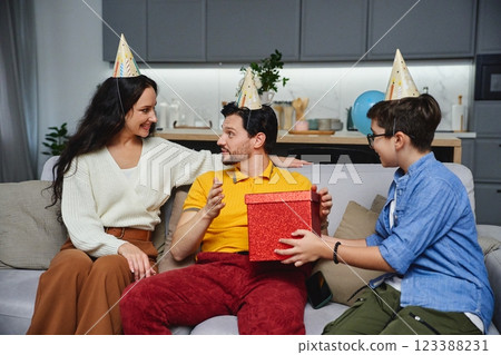 Friends celebrate a birthday with party hats, gifts, and cheerful smiles 123388231