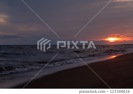 Golden hues reflect on the wet sand as the sun sets beyond the horizon, creating a peaceful ambiance on the beach. Golden hues reflect on the wet sand as the sun sets beyond the horizon, creating a peaceful ambiance on the beach. 123388616