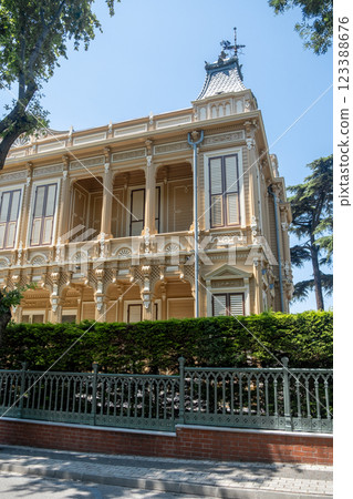 An elegant historic mansion features intricate details and lush greenery, providing a striking view on a bright sunny afternoon. 123388676