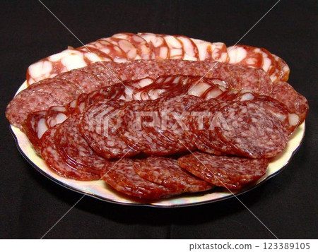 Slices of sausage and lard on a plate over solid background 123389105