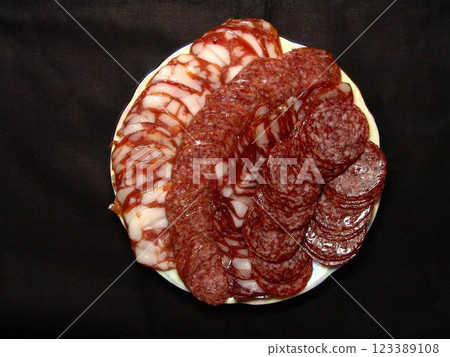 Slices of sausage and lard on a plate over solid background 123389108