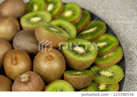 Plate of sliced and whole fresh kiwi fruit. 123390556