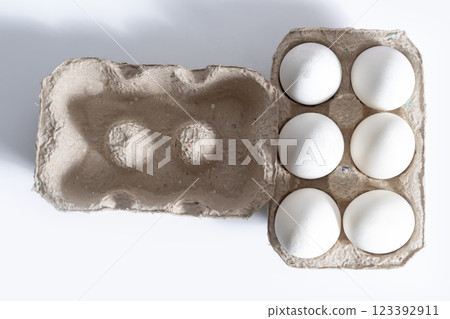 Cardboard box with six white eggs on a bright white background, top view Cardboard box with six white eggs on a bright white background, top view 123392911