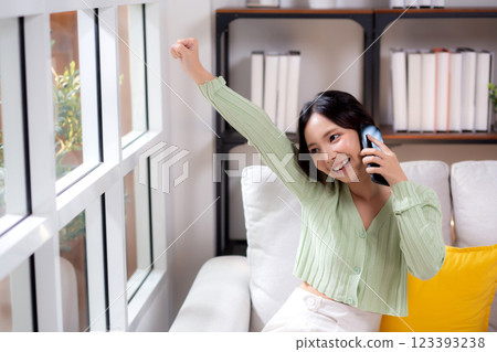 Young asian businesswoman telephone smiling and relax sitting on sofa in living room at home. 123393238