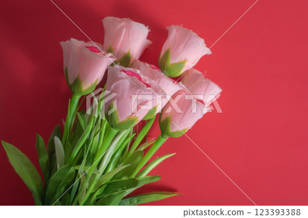 Pink artificial roses on a bright red background in studio lighting, perfect for Valentine's Day or romantic concepts. 123393388