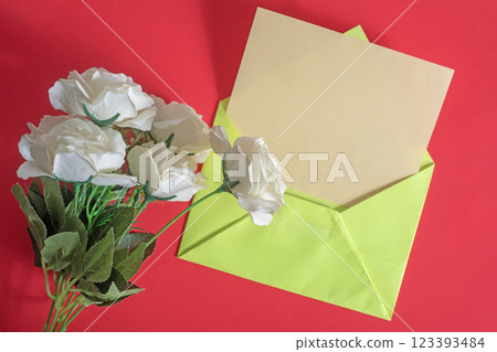 Bouquet of white roses with green envelope on red background 123393484