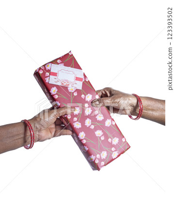 Hand holding a gift wrapped in red paper with a floral design printed on it, on a white background. Hand holding a gift wrapped in red paper with a floral design printed on it, on a white background. 123393502