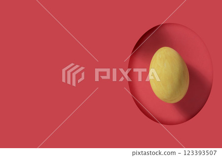 Easter greeting card. Yellow Easter egg visible through egg-shaped gap on red background with copy space. Easter greeting card. Yellow Easter egg visible through egg-shaped gap on red background with copy space. 123393507
