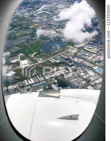 Scenic aerial view of urban landscape with clouds and water from airplane window during daytime journey 123393695