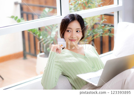 Young asian woman sitting on sofa using laptop computer shopping online with credit card. Young asian woman sitting on sofa using laptop computer shopping online with credit card. 123393895