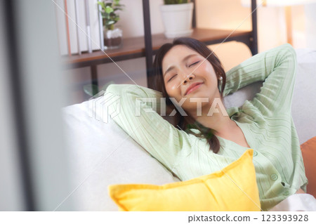 Happy young asian woman relax and leisure sitting on sofa in living room at home. 123393928