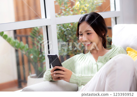 Young asian businesswoman looking smartphone smiling and relax sitting on sofa in living room. Young asian businesswoman looking smartphone smiling and relax sitting on sofa in living room. 123393952