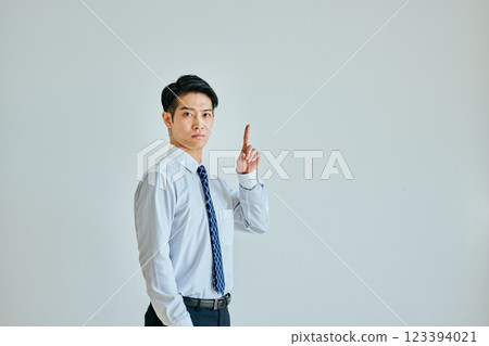 A young man in a dress shirt pointing up 123394021