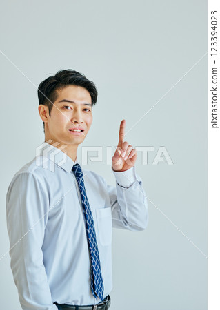A young man in a dress shirt pointing up 123394023