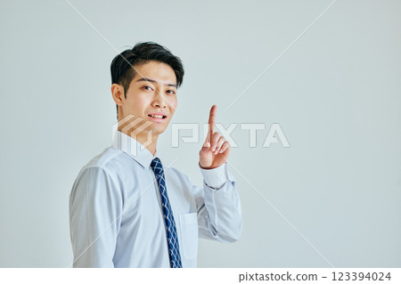 A young man in a dress shirt pointing up 123394024