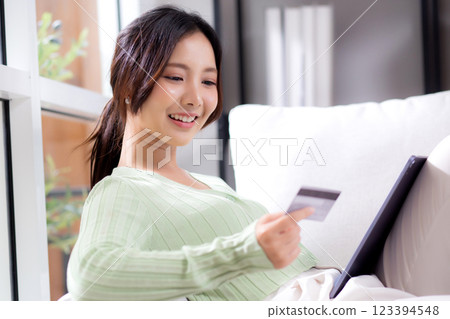 Young asian woman sitting on sofa using tablet computer shopping online with credit card. Young asian woman sitting on sofa using tablet computer shopping online with credit card. 123394548
