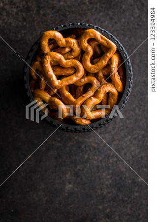 Heart shaped pretzel in bowl on black table. Top view. 123394984
