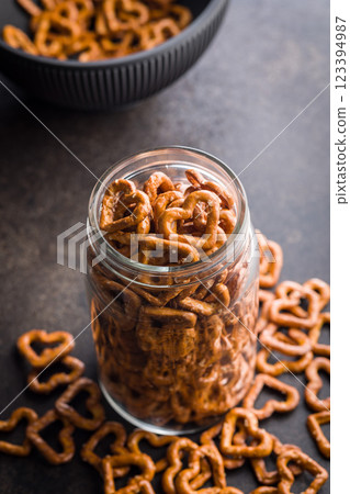 Heart shaped pretzel in jar on black table. 123394987