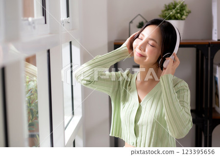 Portrait happy young woman wearing headphones listening music while standing with fun and enjoy. 123395656