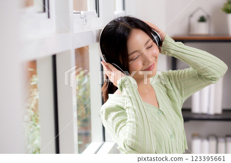 Portrait happy young woman wearing headphones listening music while standing with fun and enjoy. Portrait happy young woman wearing headphones listening music while standing with fun and enjoy. 123395661