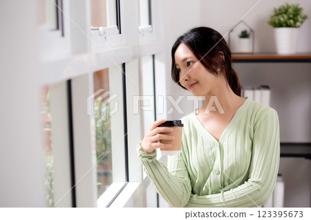 Portrait young asian woman relax and enjoyment with drinking coffee by the window in living room. Portrait young asian woman relax and enjoyment with drinking coffee by the window in living room. 123395673