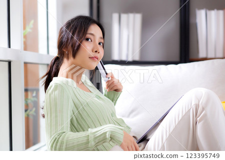 Young asian woman sitting on sofa using tablet computer shopping online with credit card. 123395749