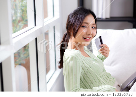 Young asian woman sitting on sofa using tablet computer shopping online with credit card. 123395753