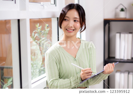 Young asian woman using tablet writing with inspiration and comfortable by window. Young asian woman using tablet writing with inspiration and comfortable by window. 123395912