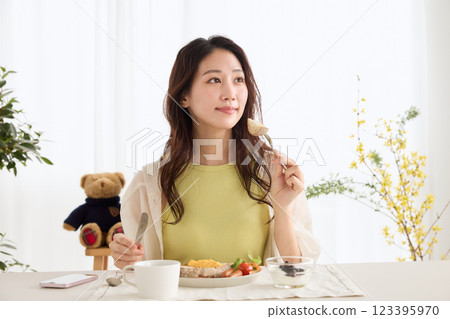 Woman eating breakfast in the dining room 123395970