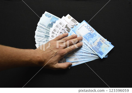 a bundle of Russian rubles is covered with a man's hand a bundle of Russian rubles is covered with a man's hand 123396059