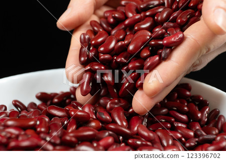Hands pouring raw uncooked red kidney beans close-up 123396702