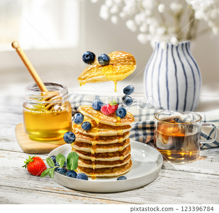 Delicious and Mouthwatering Pancakes Artfully Topped with Fresh Berries and Golden Honey Delicious and Mouthwatering Pancakes Artfully Topped with Fresh Berries and Golden Honey 123396784