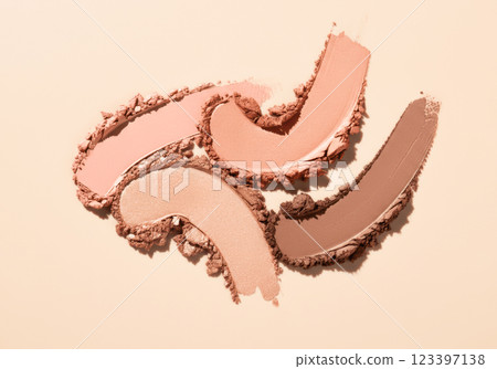 Assorted neutral eyeshadow swatches on beige surface for makeup inspiration 123397138