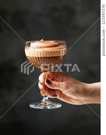 Elegant espresso martini in a crystal glass held by female hand 123397376