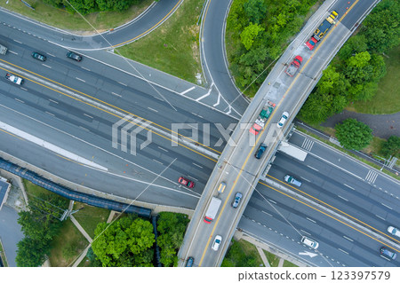 Vehicles travel through complex highway interchange surrounded by greenery near American town at New Jersey 123397579