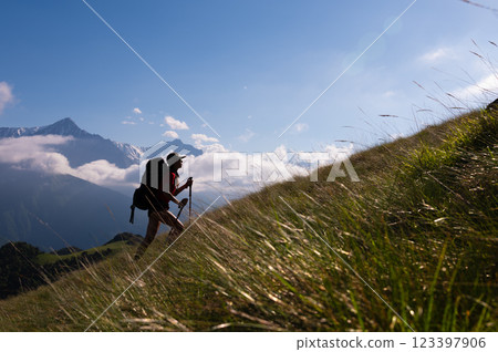 Hiking, travel adventures, tourist recreation in the fresh air, healthy lifestyle, ecotourism. Young woman with a backpack climbs a mountain Hiking, travel adventures, tourist recreation in the fresh air, healthy lifestyle, ecotourism. Young woman with a backpack climbs a mountain 123397906