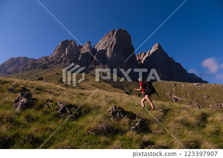 Hiking, travel adventures, tourist recreation in the fresh air, healthy lifestyle, ecotourism. Young woman with a backpack climbs a mountain Hiking, travel adventures, tourist recreation in the fresh air, healthy lifestyle, ecotourism. Young woman with a backpack climbs a mountain 123397907
